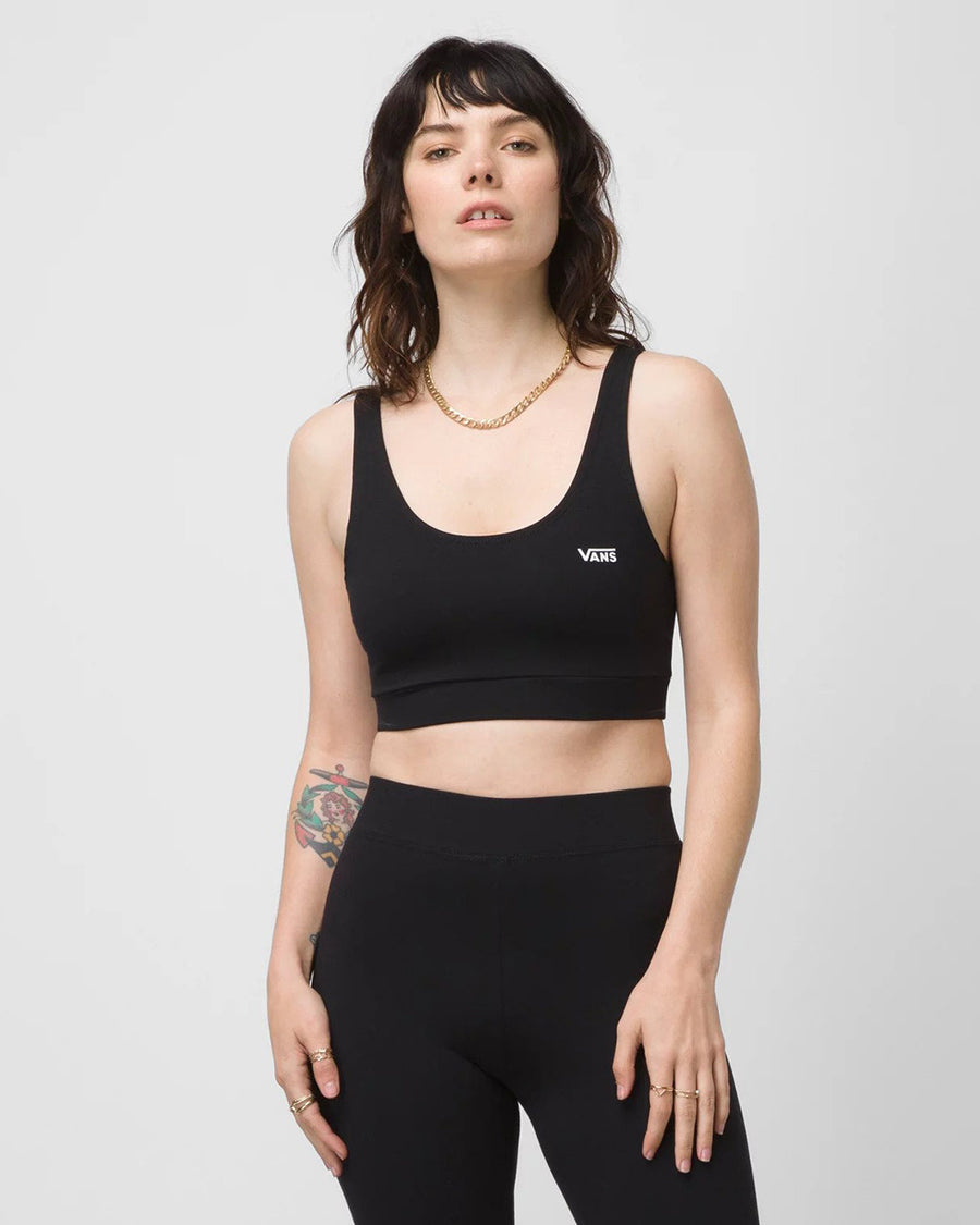 model wearing black vans bralette with white vans logo on top left side corner and matching black leggings