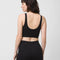 backview of model wearing black vans bralette with white vans logo on top left side corner and matching black leggings