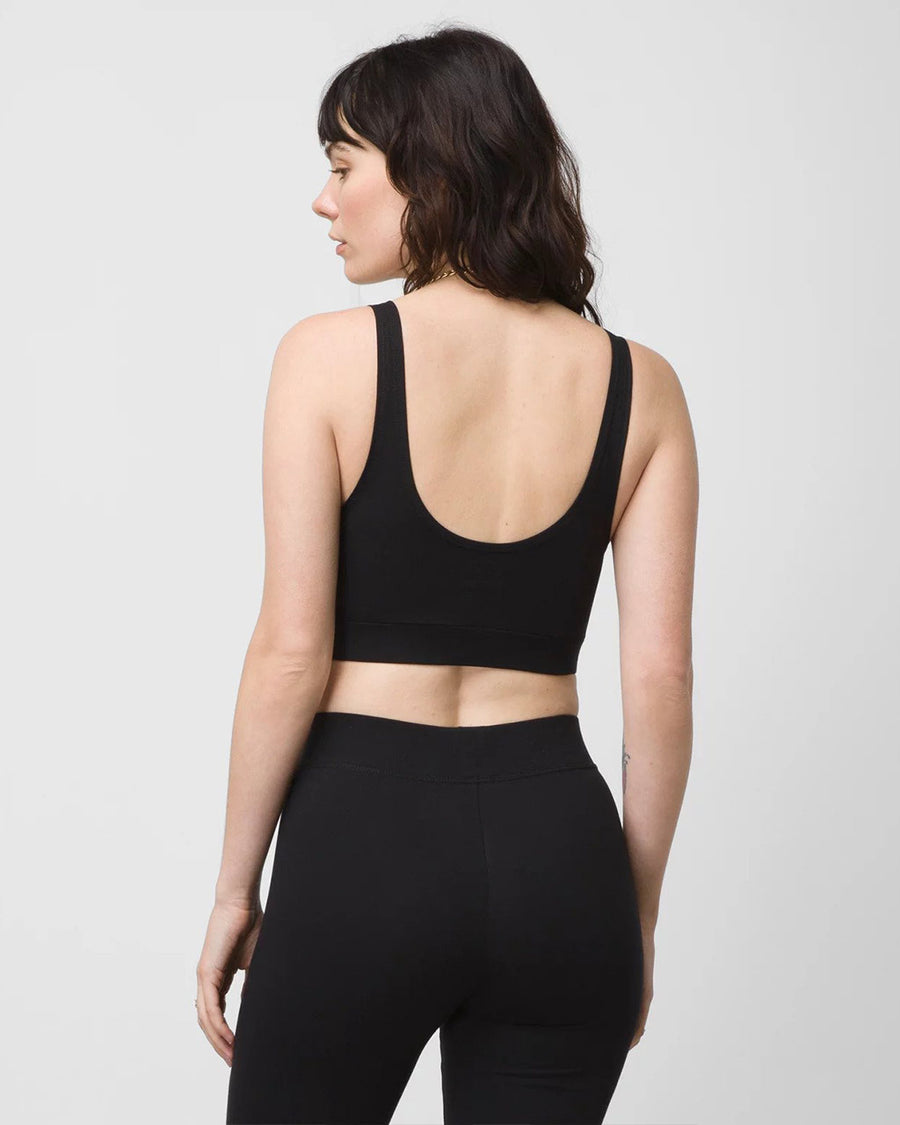 backview of model wearing black vans bralette with white vans logo on top left side corner and matching black leggings