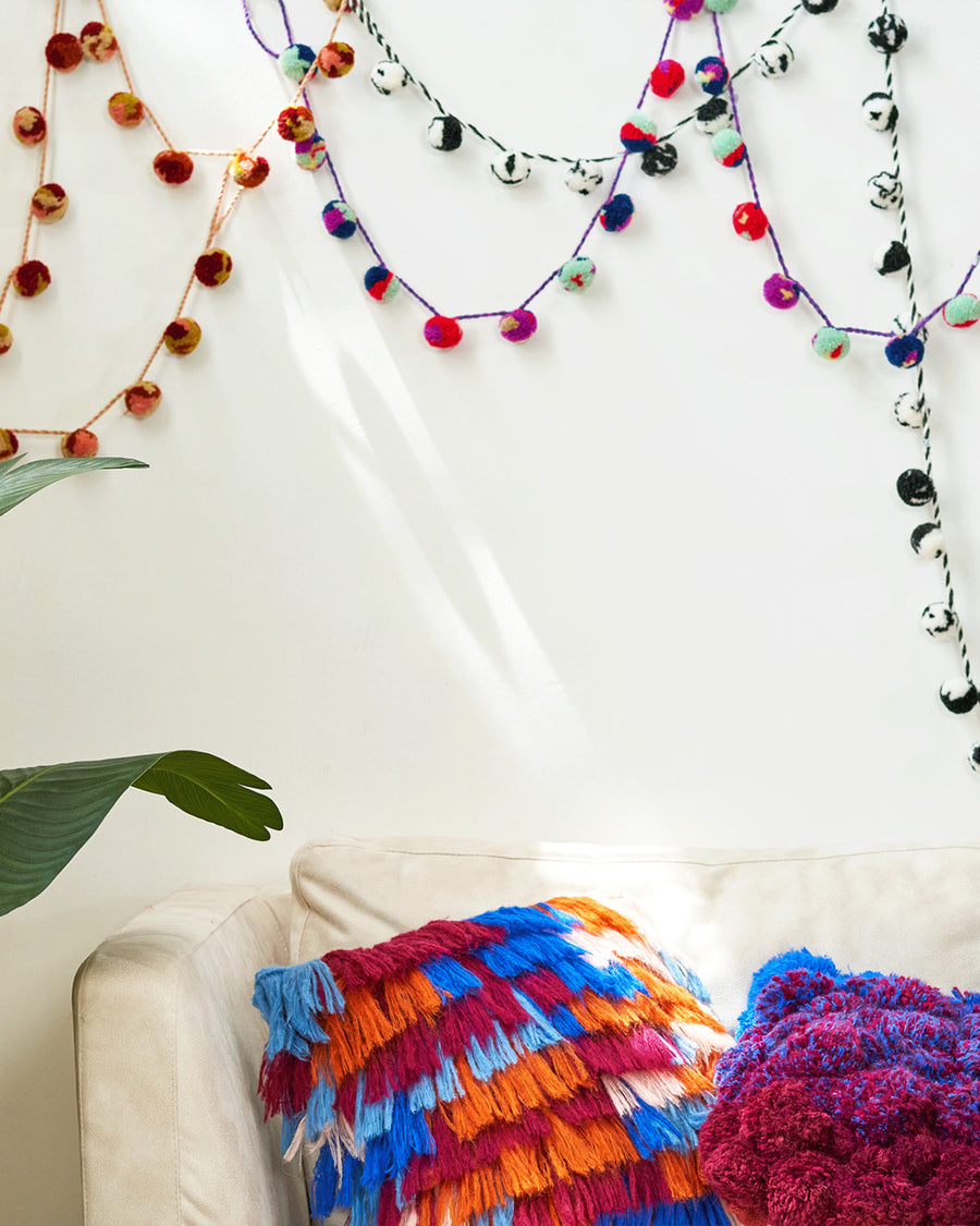 styled room with all three color ways of pom garland and colorful throw pillows