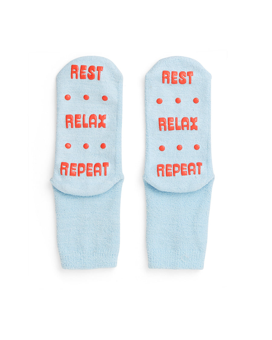 blue, fuzzy socks with 'REST, RELAX, REPEAT' in red grip material