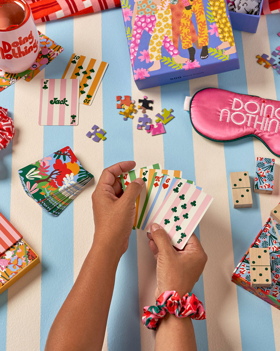 hands holding a set of playing cards against a backdrop of games and leisure items