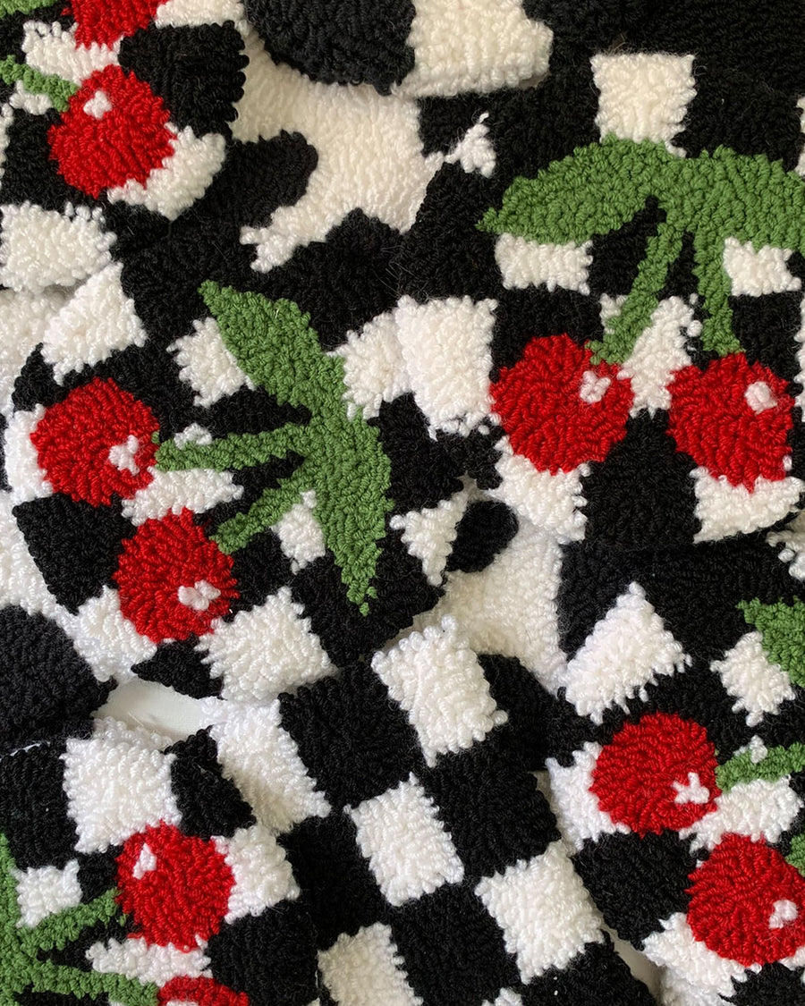 pile of round rug mugs with black and white checker with red cherry design