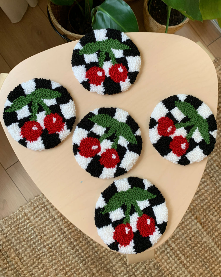 round rug mugs with black and white checker with red cherry design on a table